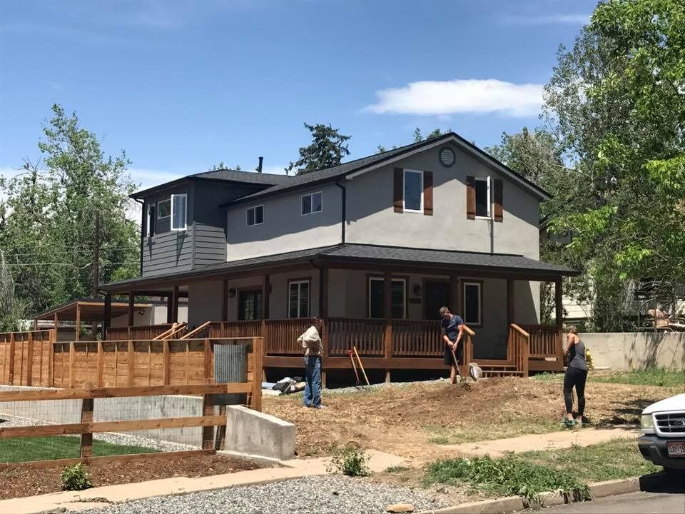 Two-story house under construction with workers and a truck in the yard