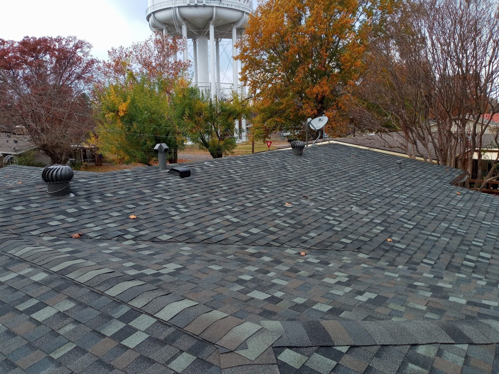 Cobblestone plaza with autumn trees and a water tower in the background