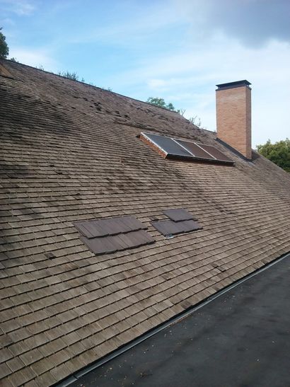 Green gutter on a dark gray shingled roof, with a close-up view of the roof edge