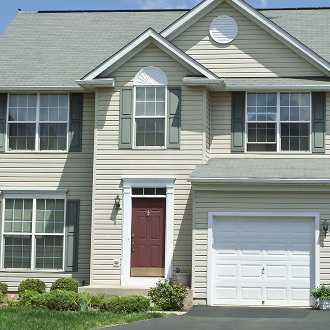 Two-story beige suburban house with white garage door and red front door