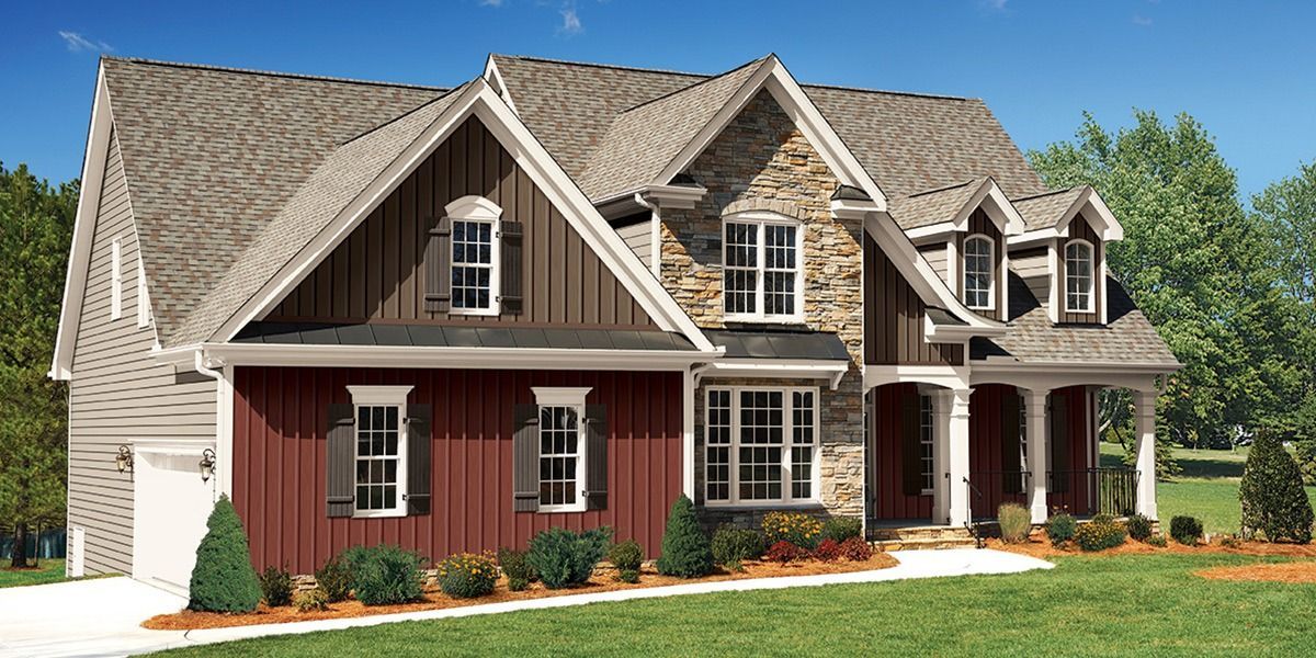 Two-story red and beige suburban house with a gabled roof and front porch under a clear sky