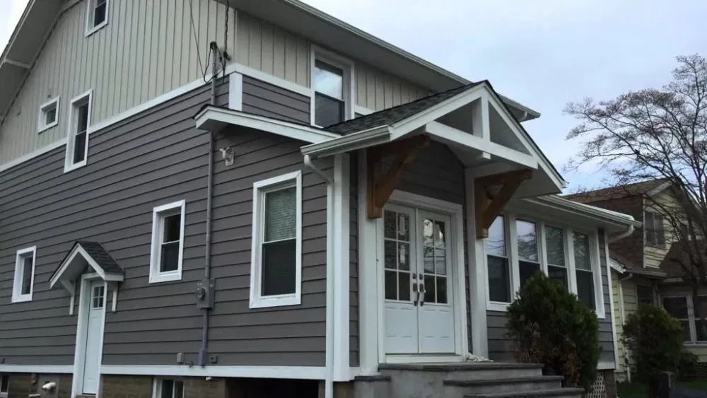 Gray two-story house with white trim, front porch, and gabled roof