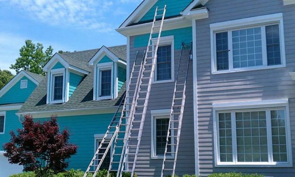 Two-story houses with ladders leaning against the siding during exterior painting work