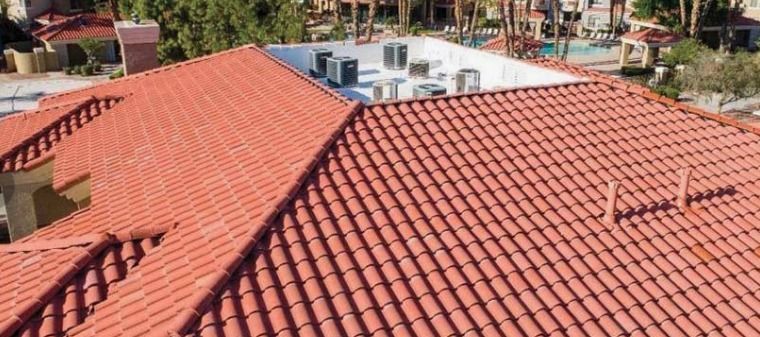 Red-tiled house rooftops with rooftop vents and a distant street view