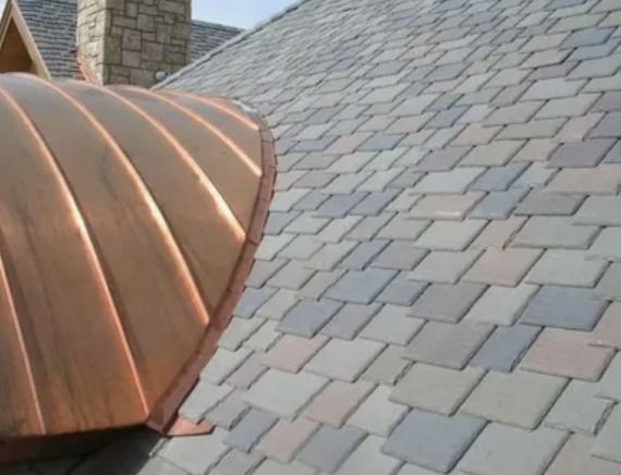 Copper-clad turret roof with gray shingles and a stone chimney
