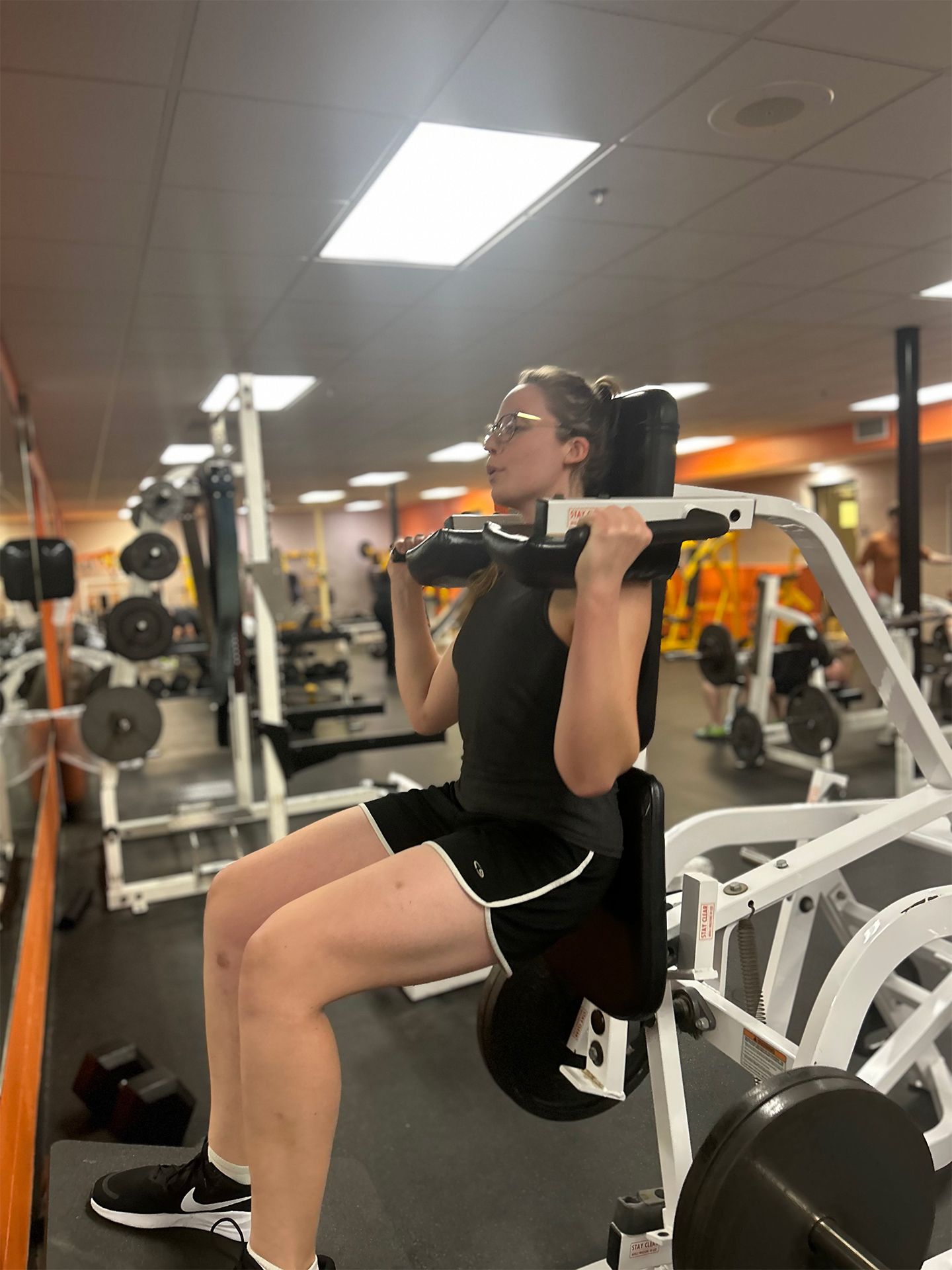 Woman using a seated squat machine at a gym.