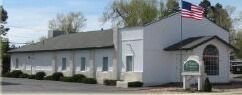 White building with American flag; sign in front.