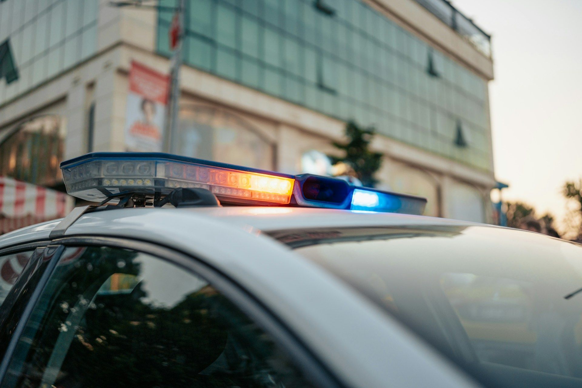 Police car with flashing blue and amber lights, parked in front of a building.