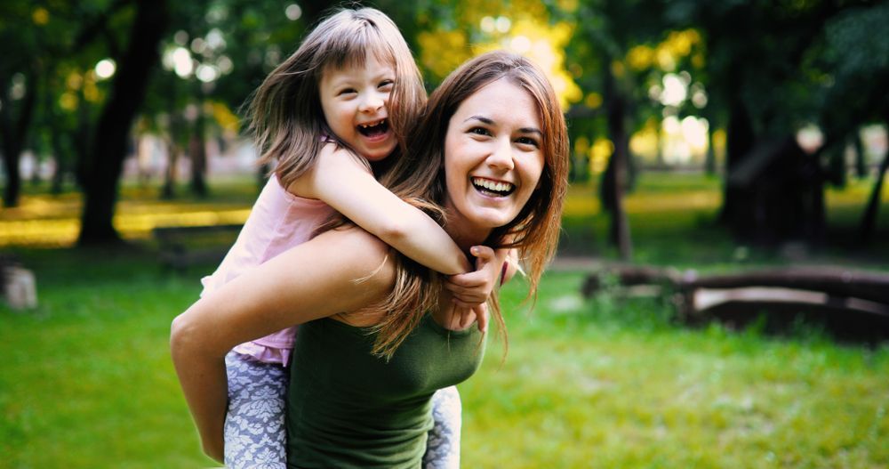 Little Girl With Special Needs Getting a Piggyback From Young Woman — Active Lifestyle Supports In Tullimbar, NSW