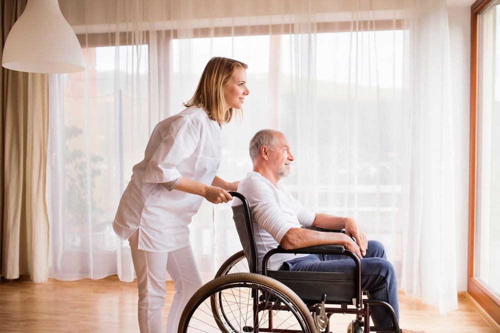  A Woman Assists an Elderly Man in a Wheelchair — Active Lifestyle Supports In Tullimbar, NSW