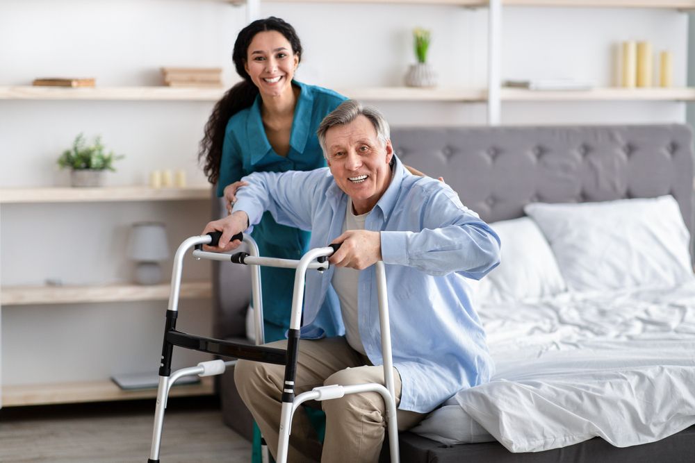 Female Nurse Helping Elderly Male With Walking Frame to Stand — Active Lifestyle Supports In Tullimbar, NSW