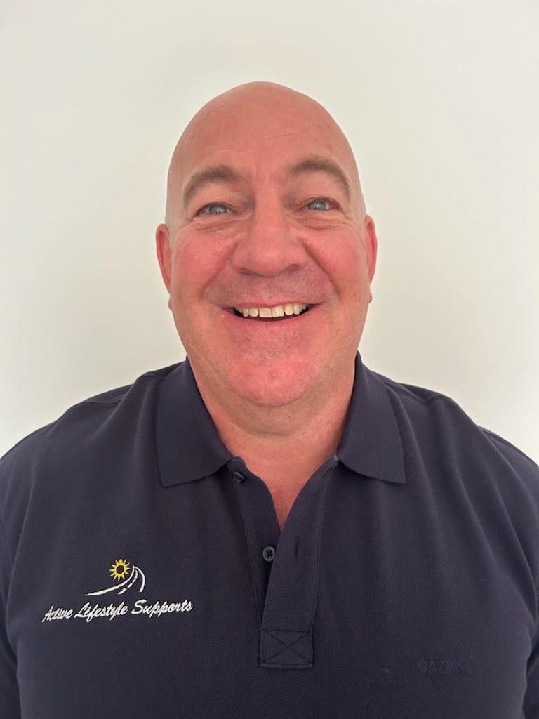 A man in a blue polo is smiling for the camera — Active Lifestyle Supports In Tullimbar, NSW