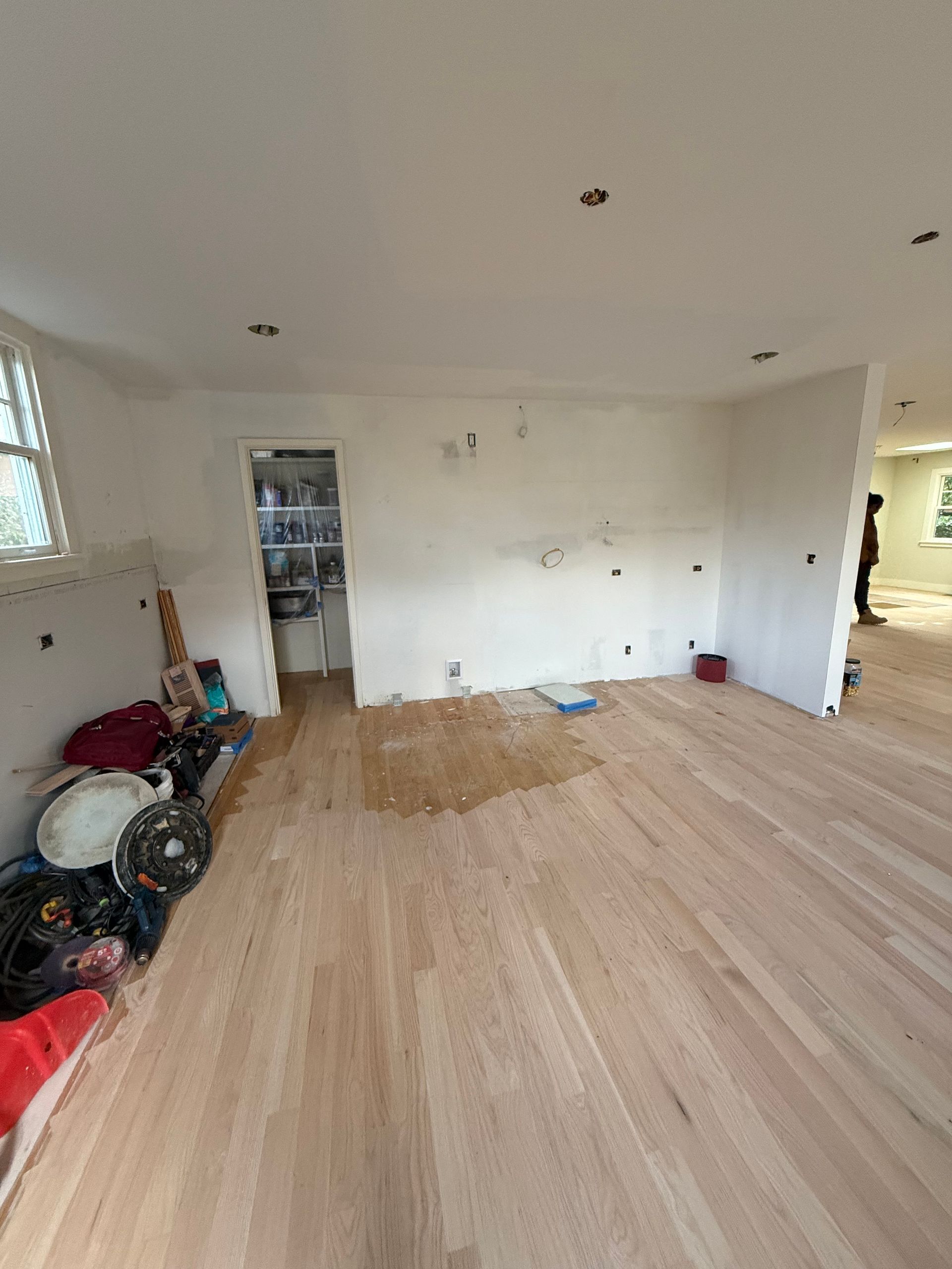 A room under construction featuring an orange waterproof floor membrane, unfinished walls, and a shower curb installation.