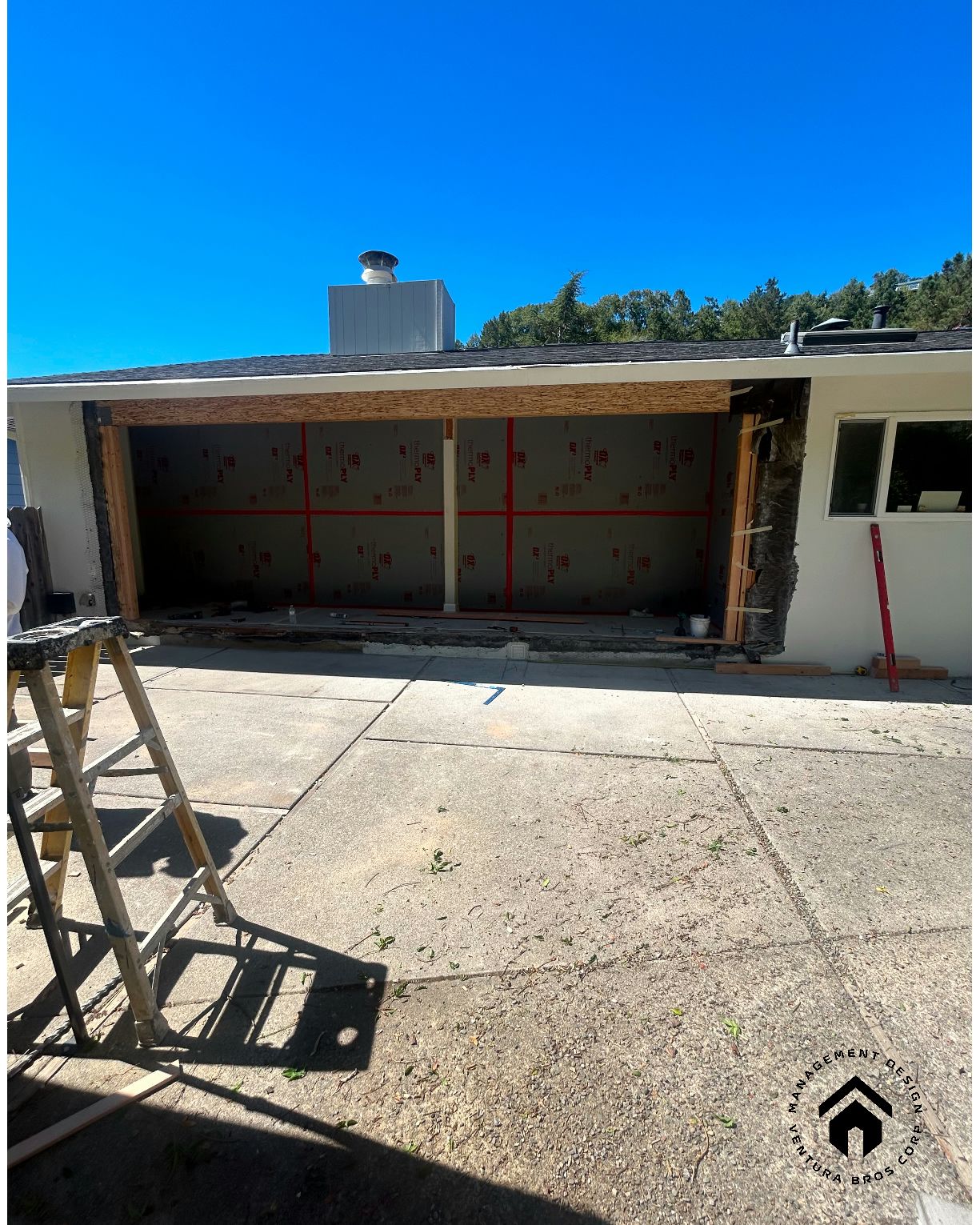 A house exterior under construction with a large, open garage bay and a wooden frame supporting the roof.