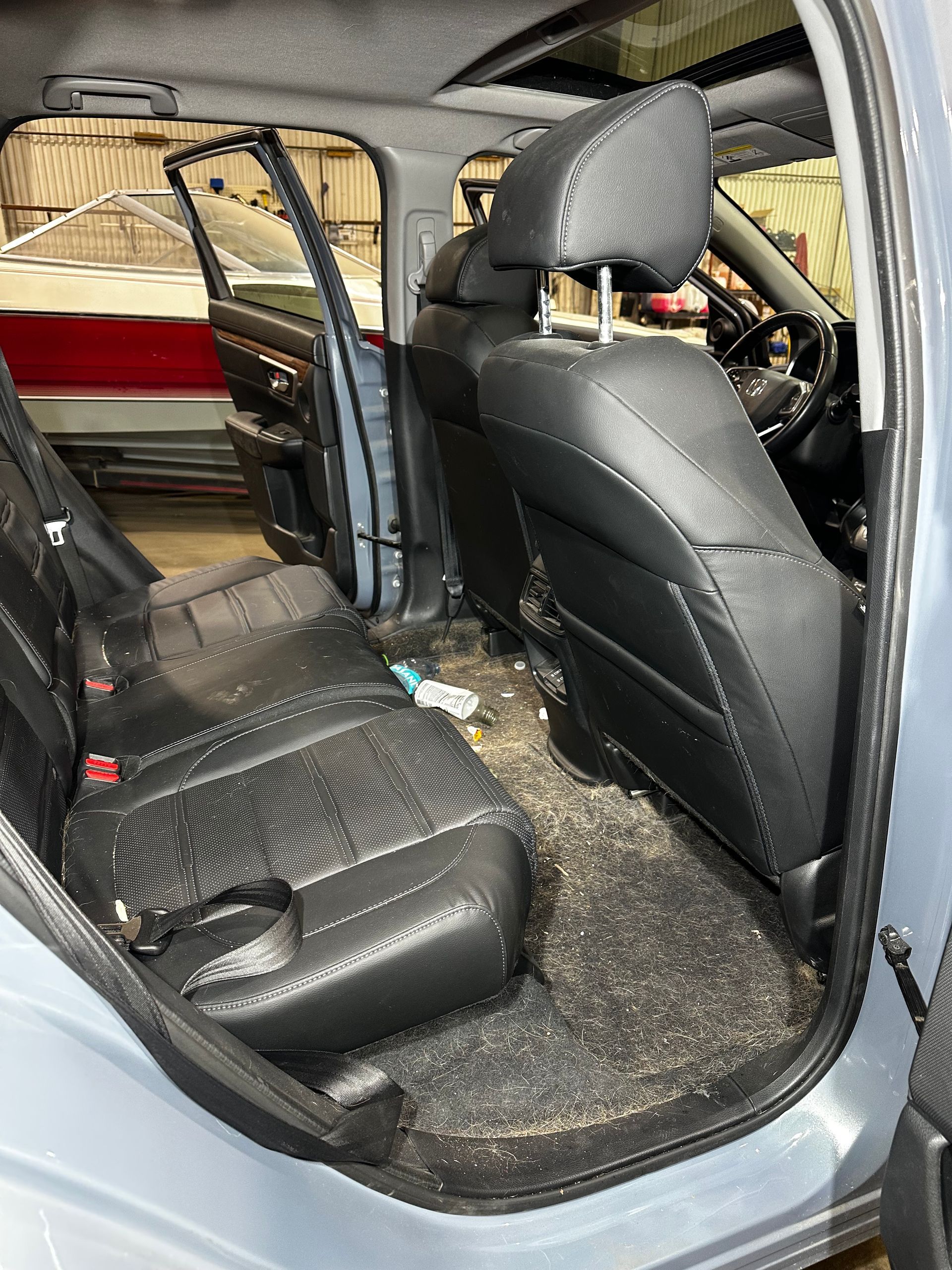 Car interior with black seats and dashboard, showing a dirty, debris-strewn floor and center console area