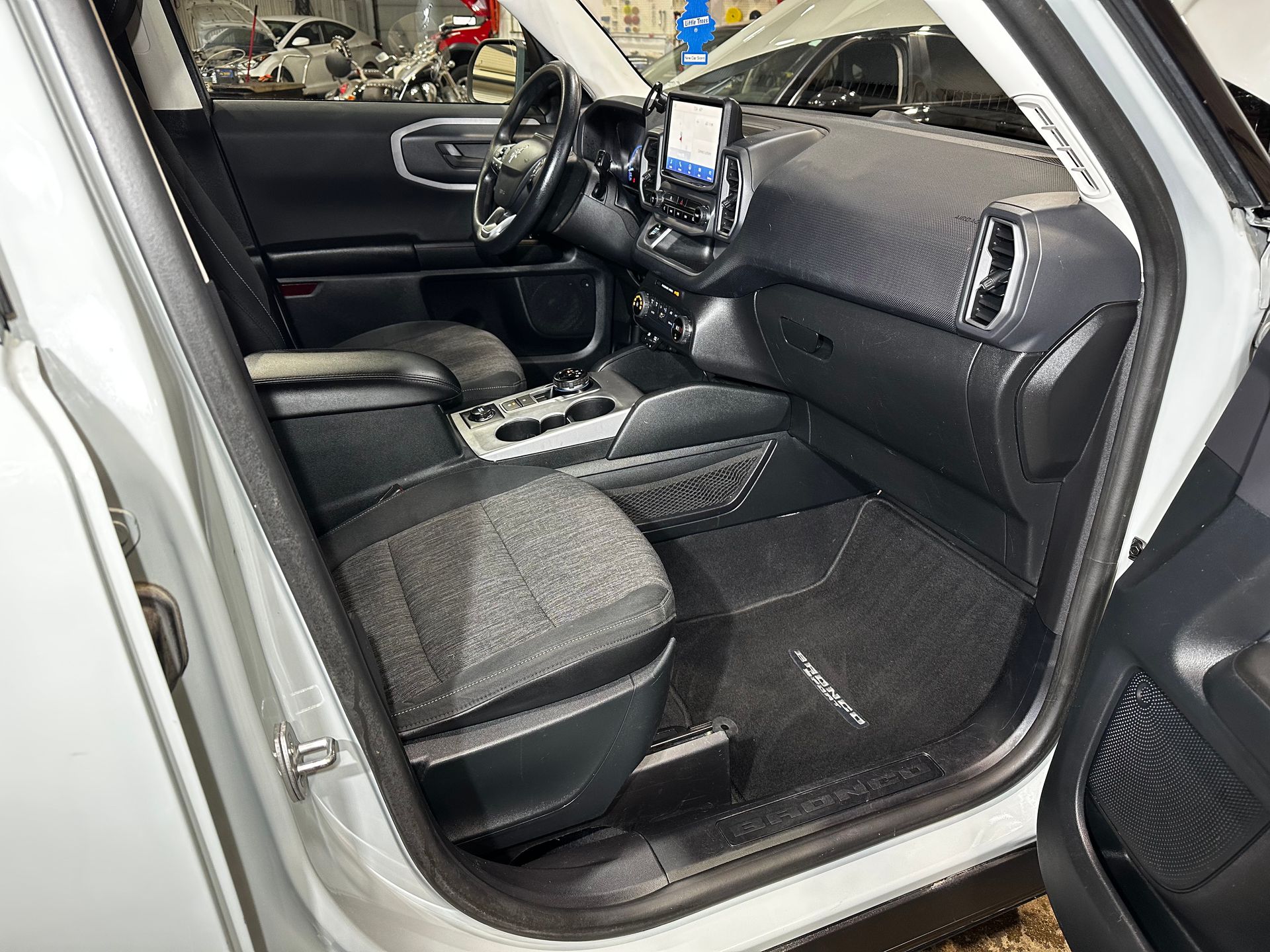 Car interior with gray seats, black dashboard, and the front passenger door open