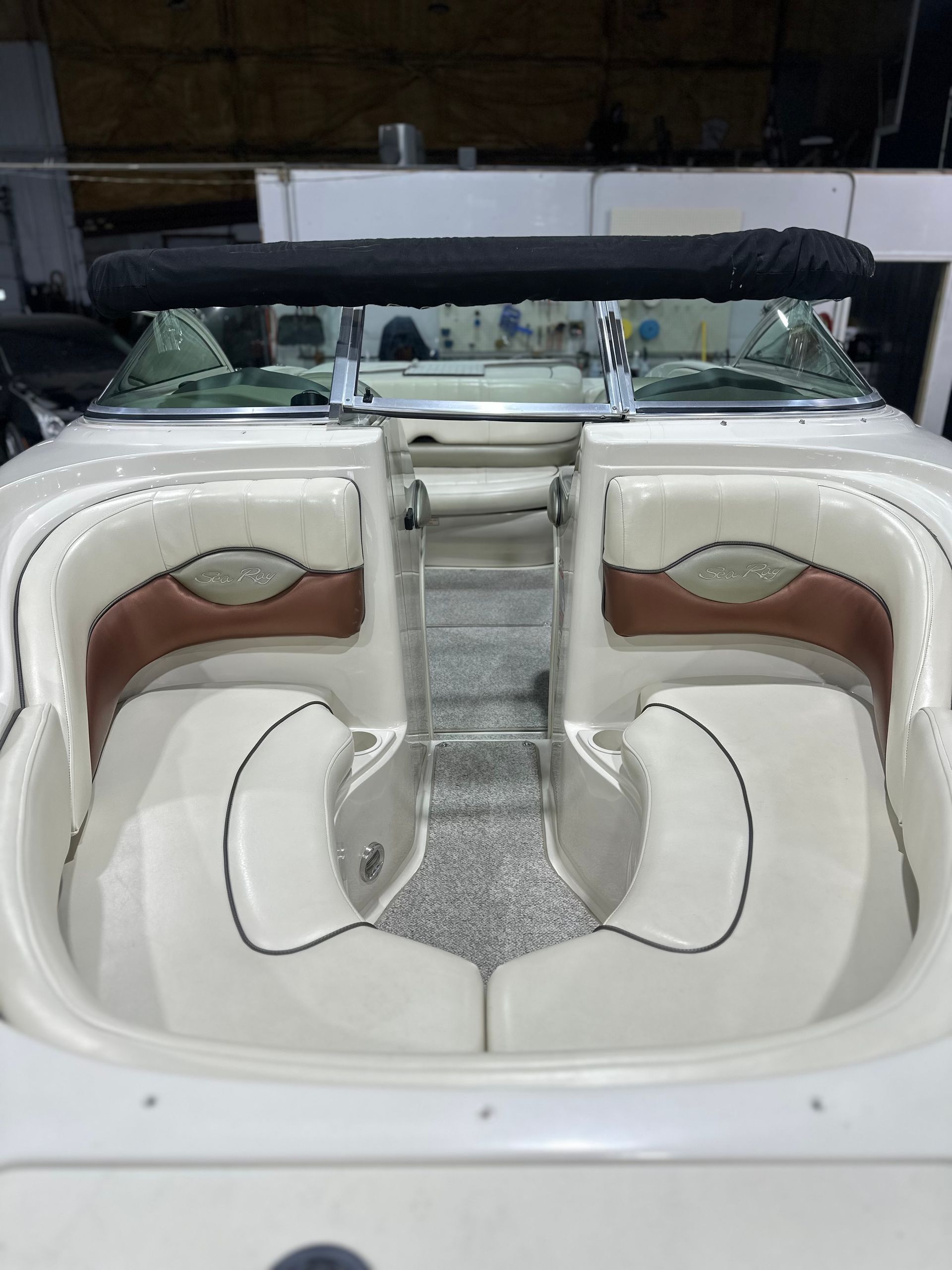 White boat cockpit with U-shaped cream seating and a central passageway, viewed from the stern