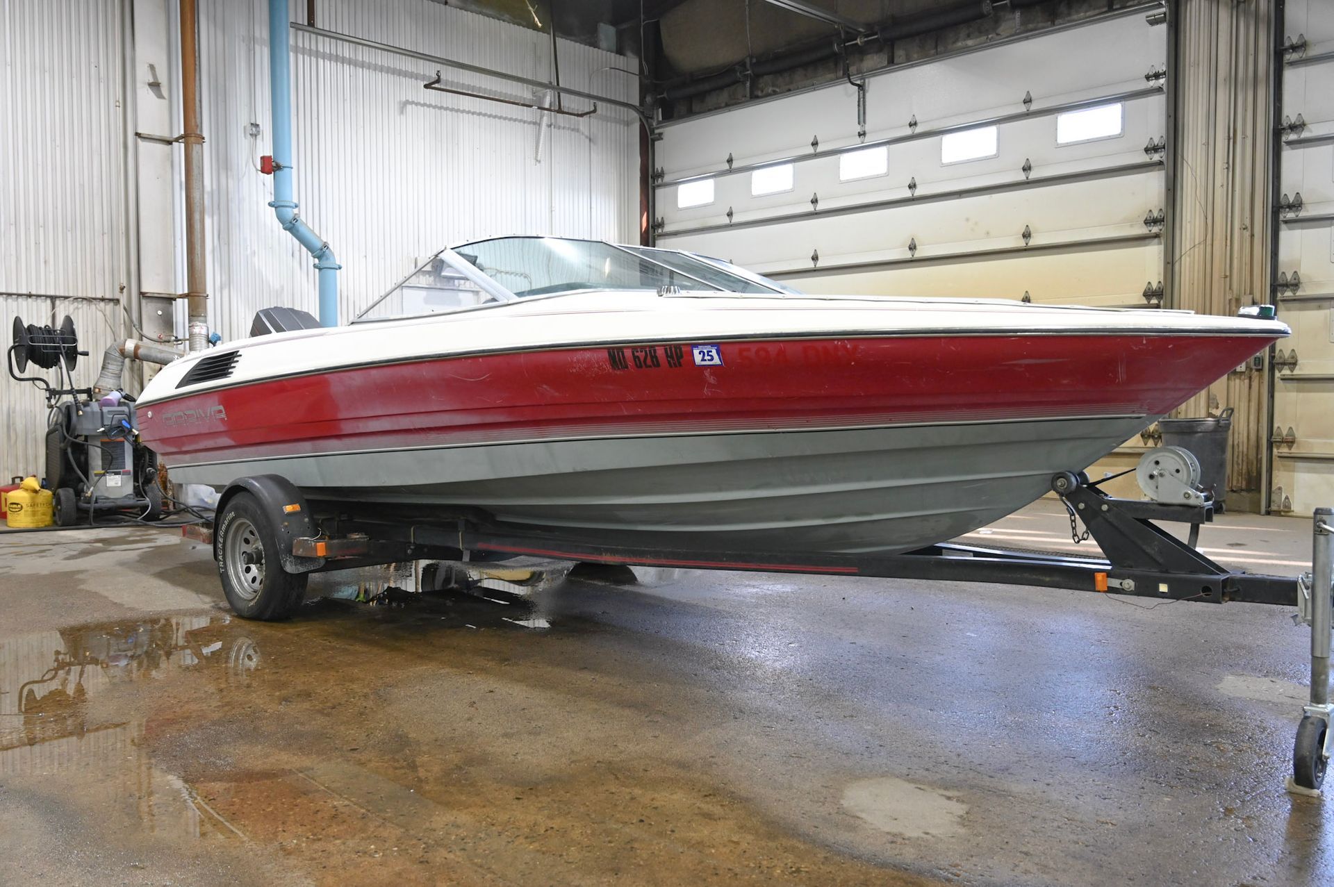 Red and silver speedboat on a trailer inside a wet boat repair garage