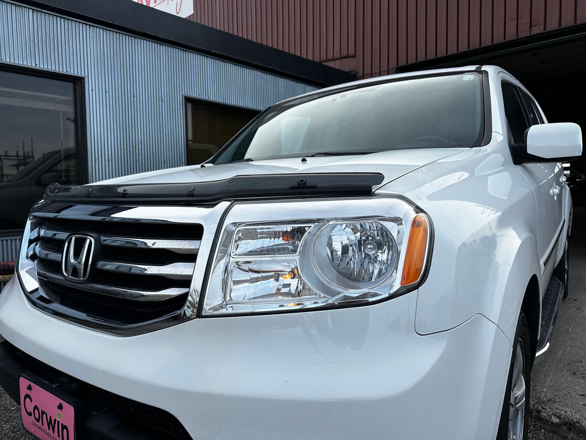 White Honda SUV parked outside a building with black-and-white siding