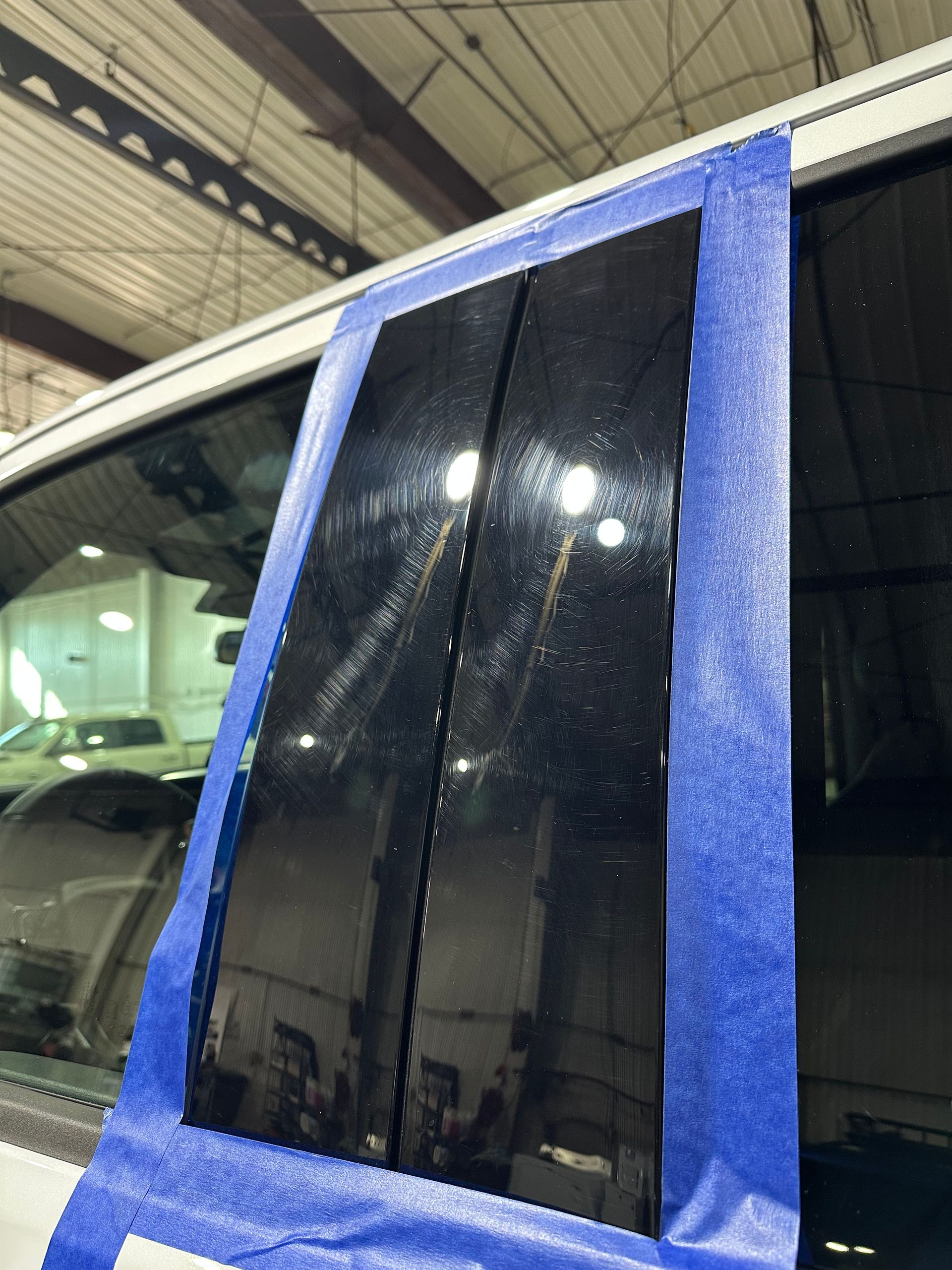 Blue-taped car window with dark tinted glass under a covered parking structure