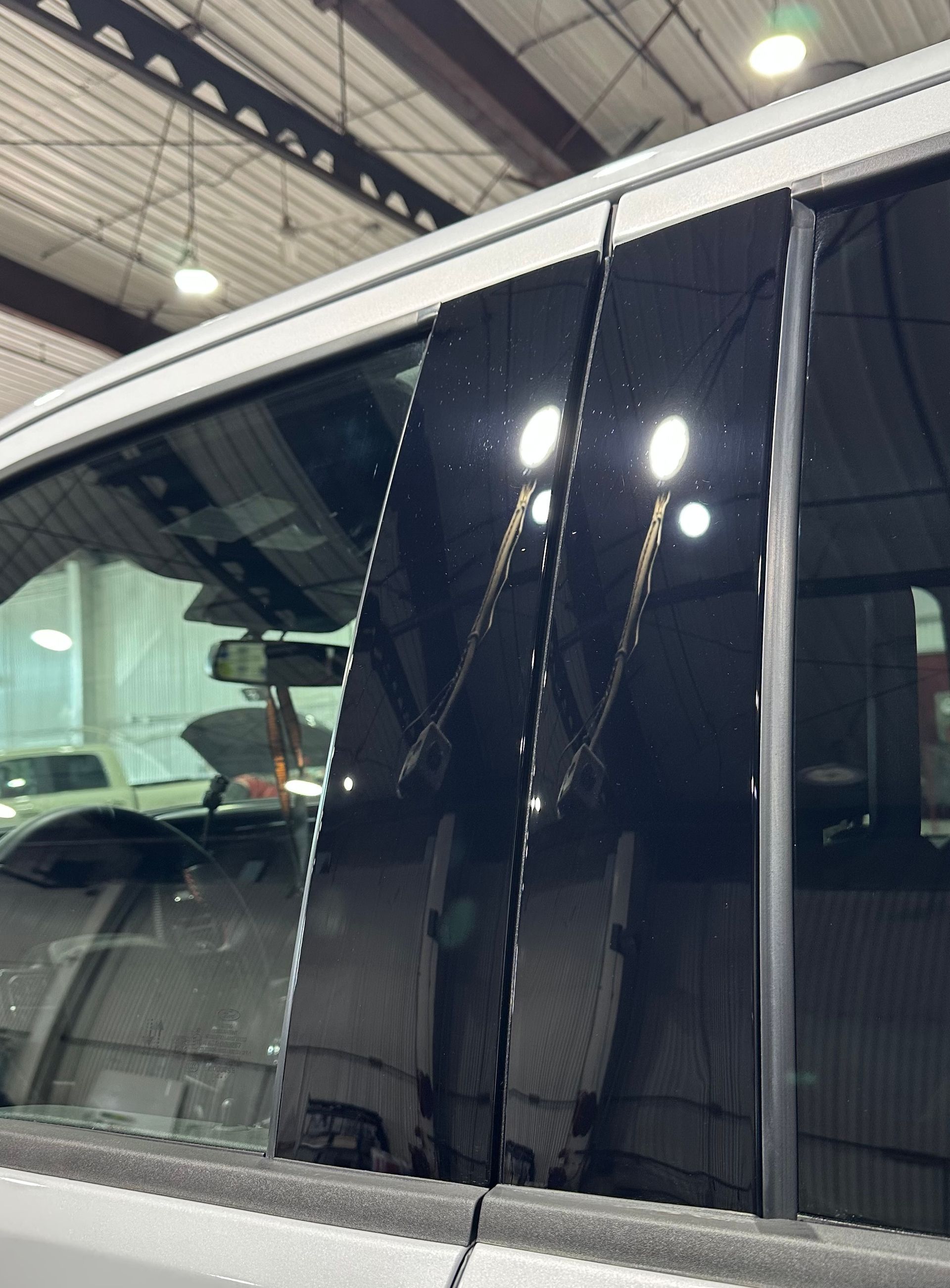 Close-up of a car window with several vertical cracks under bright indoor lights