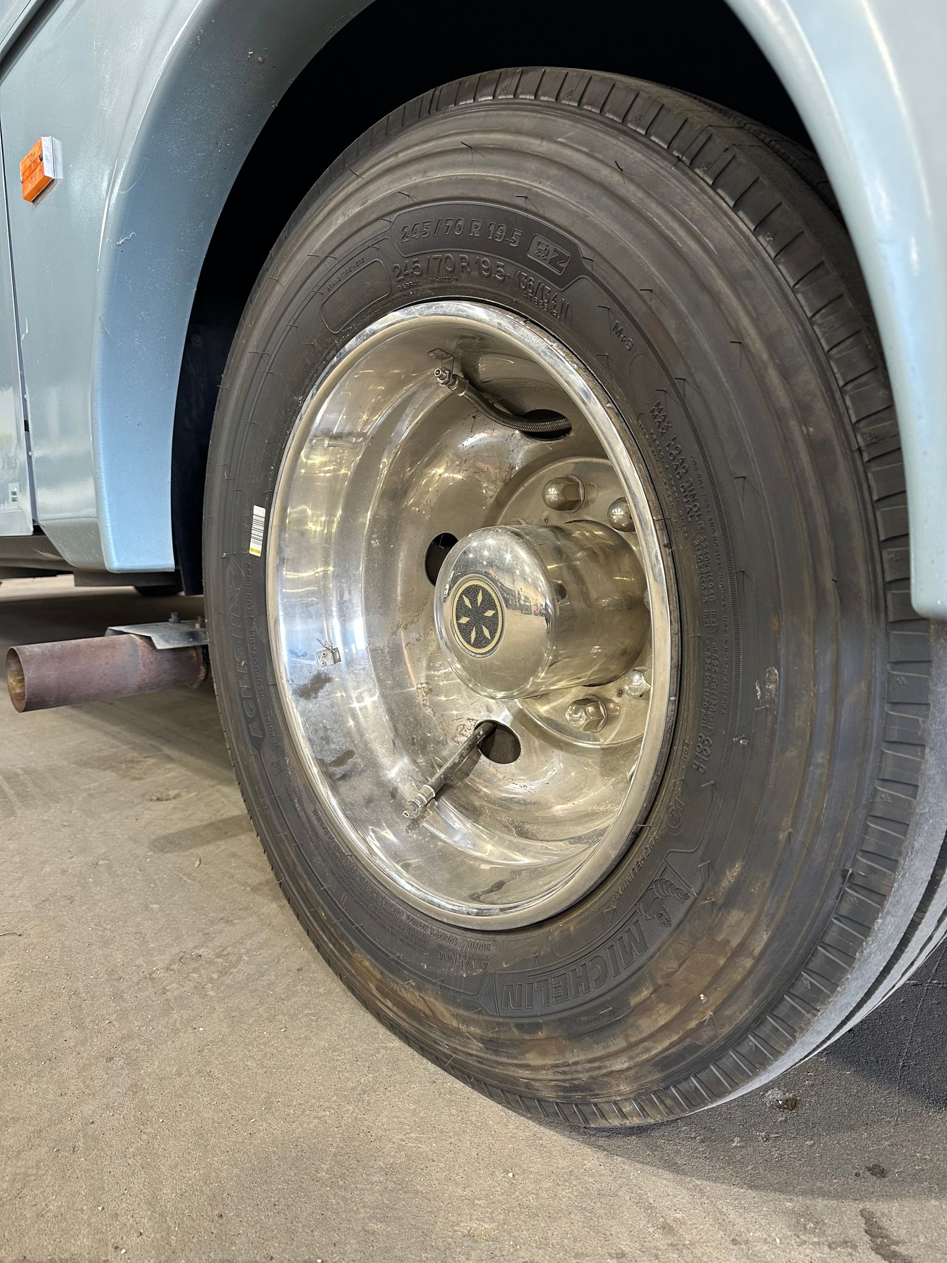 Close-up of a blue vehicle’s rear wheel with a shiny chrome rim parked on a concrete floor