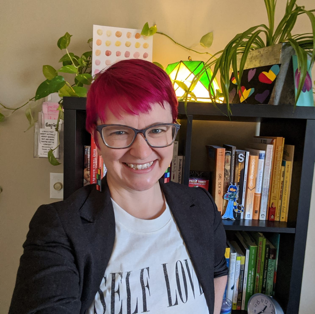 A woman wearing glasses and a shirt that says self love