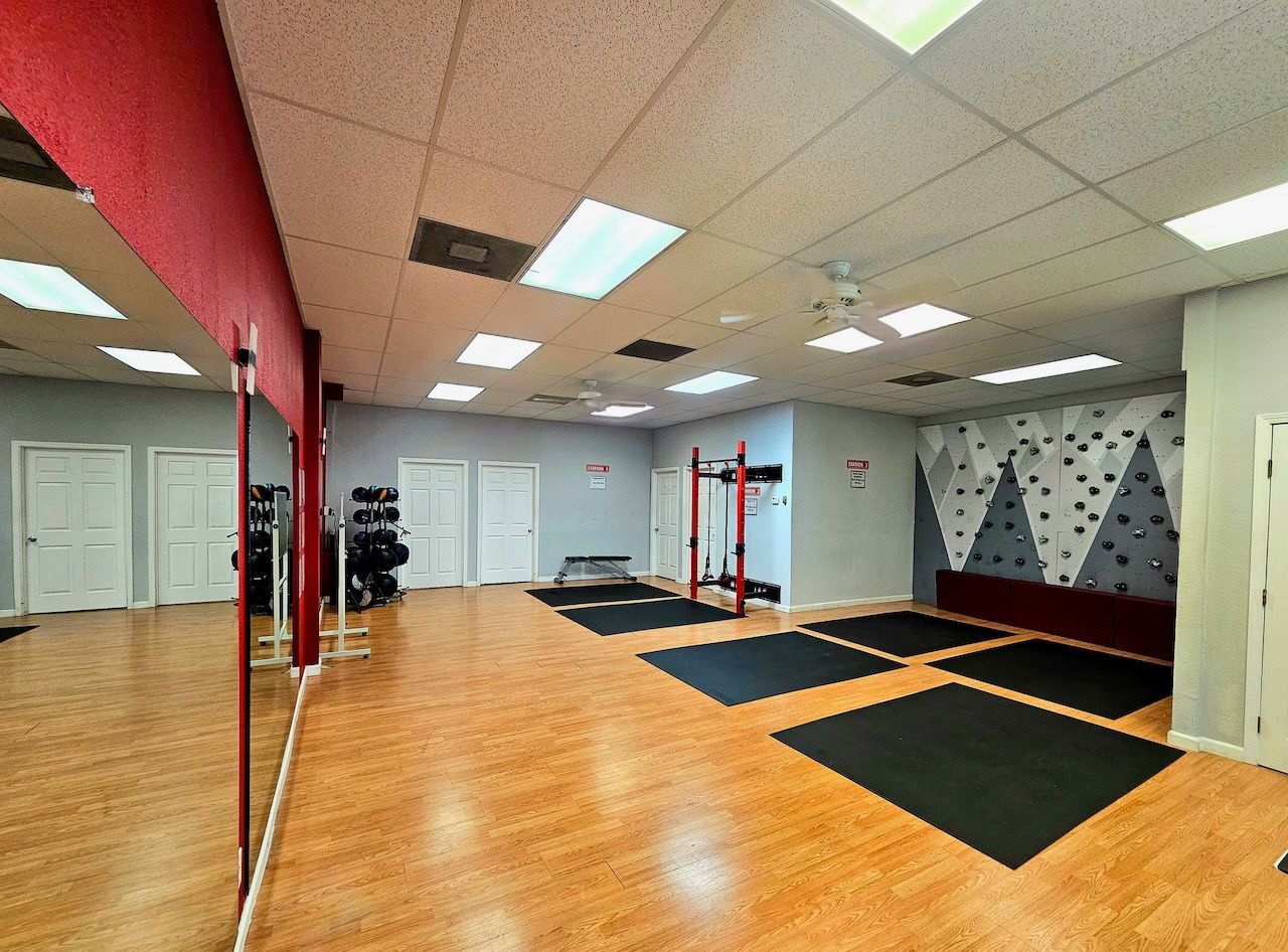 A large empty gym with a lot of mirrors and a climbing wall.