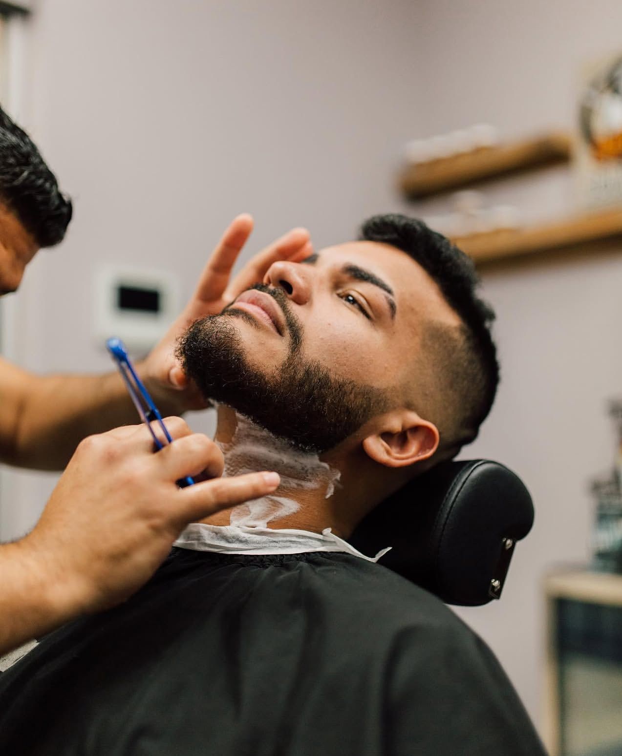 Barber using electric clippers to fade the back of a short haircut