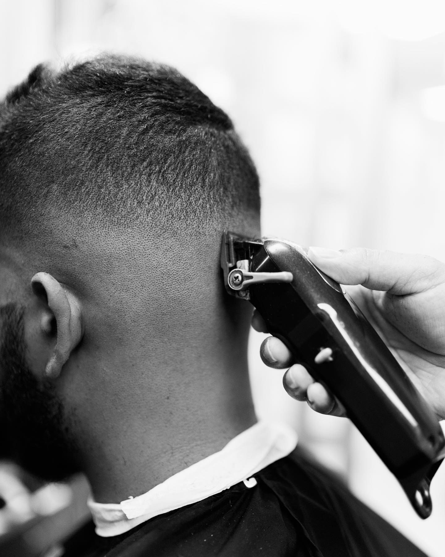 Barber using electric clippers to fade the back of a short haircut