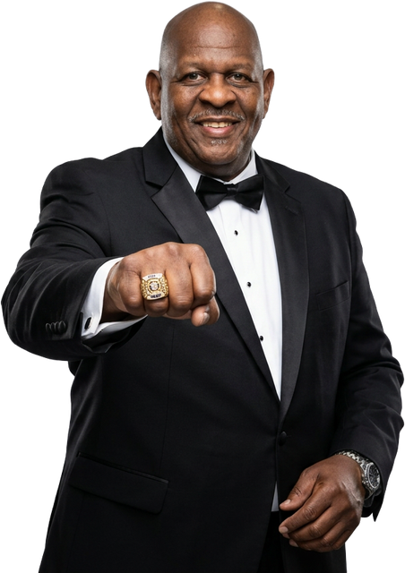 Man in a black tuxedo pointing toward the camera against a white background