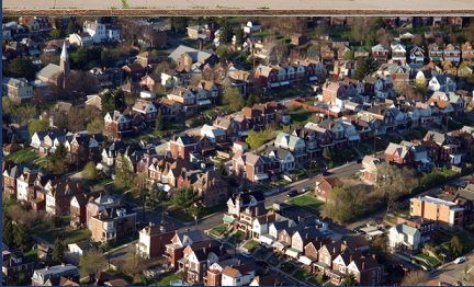 Aerial view of a dense residential neighborhood with many brick houses and tree-lined streets.