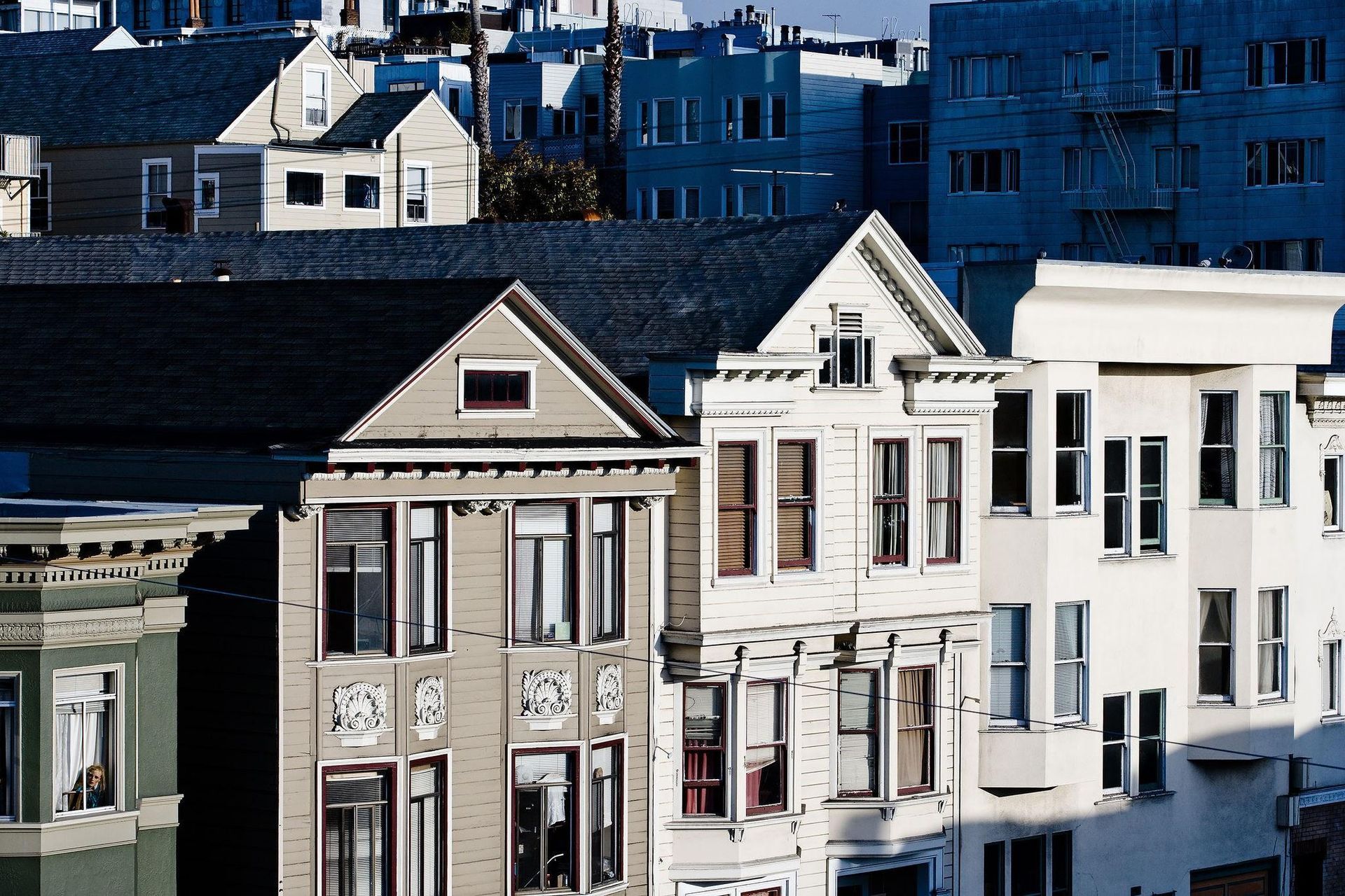 Close-up of three tall, historic Victorian-style residential buildings in San Francisco under bright daylight.