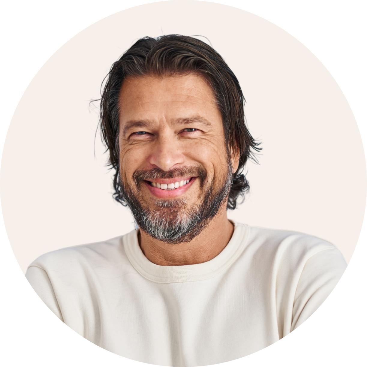 a man with long hair and a beard smiles for the camera