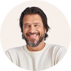 a man with long hair and a beard smiles for the camera