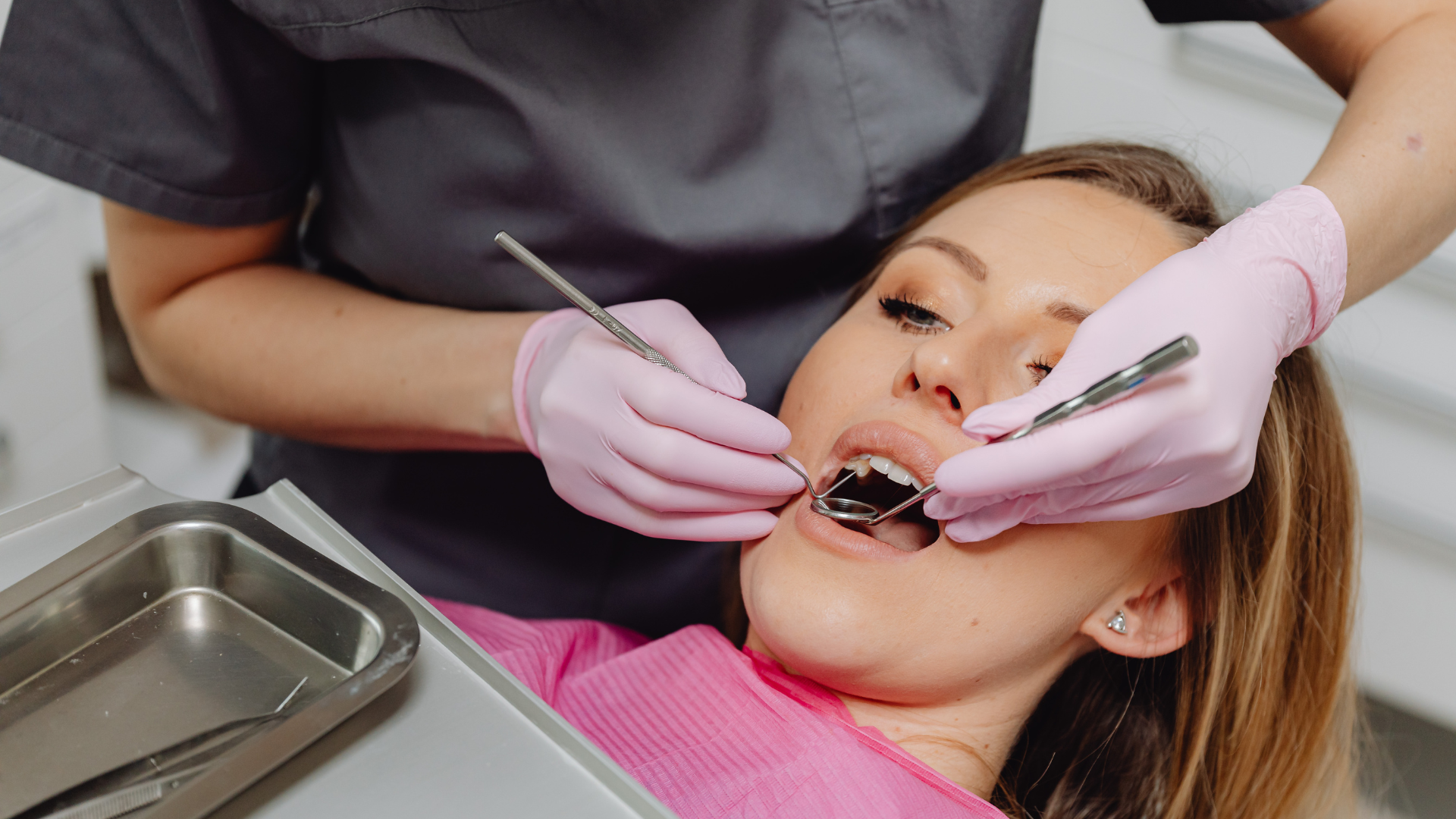 Dentist examining a patient's teeth with dental tools in an office setting.