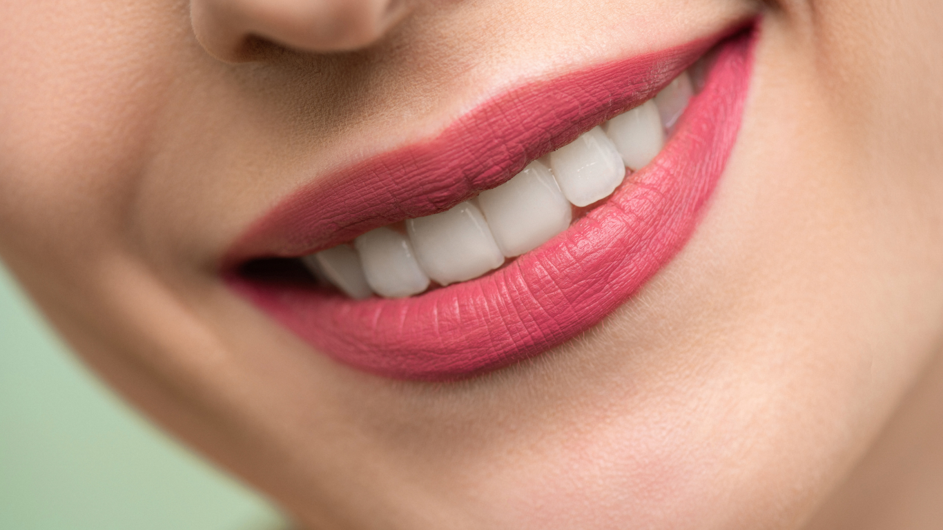 Close-up of a smiling mouth with pink lipstick and white teeth