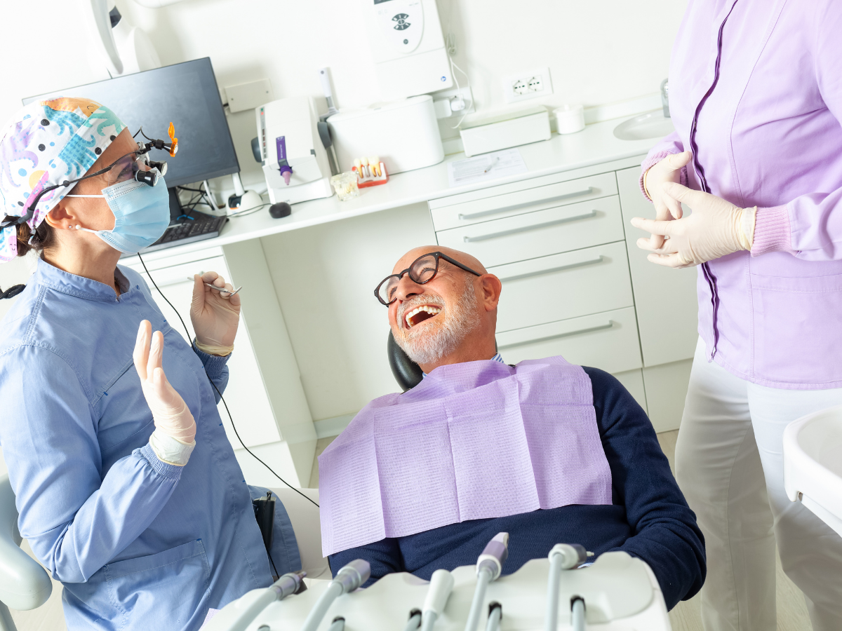 Dentist and assistant in dental office with a laughing patient.