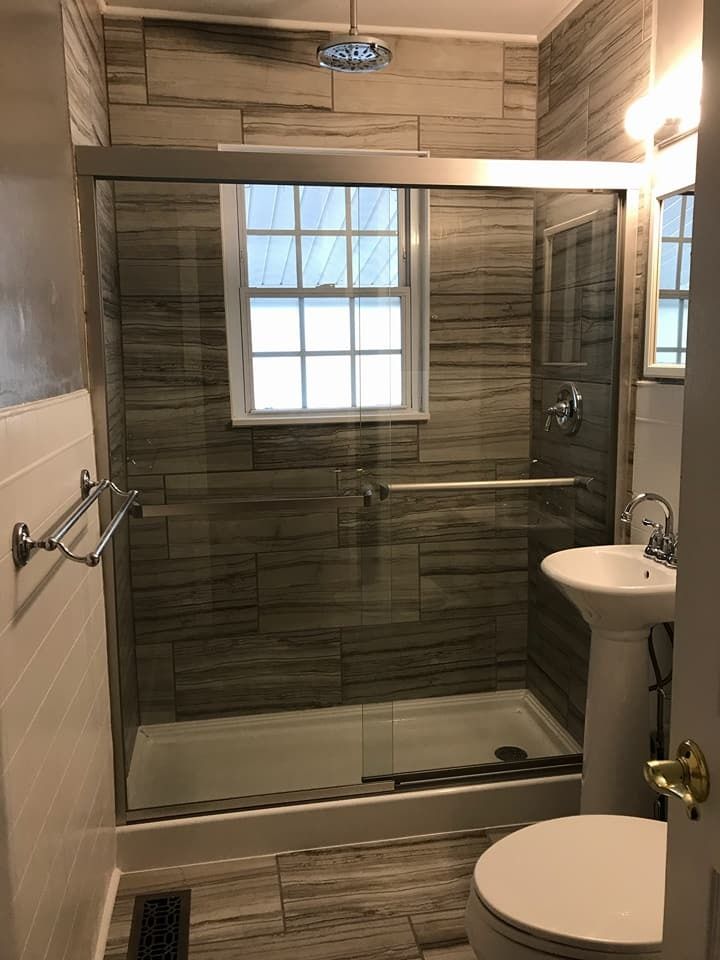Bathroom with tiled walls and a glass shower door; a toilet and pedestal sink are also visible.
