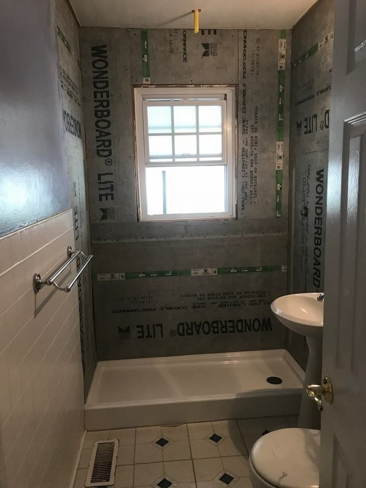Bathroom remodel in progress with Wonderboard Lite tile backer board installed. Window, sink, and shower pan are visible.