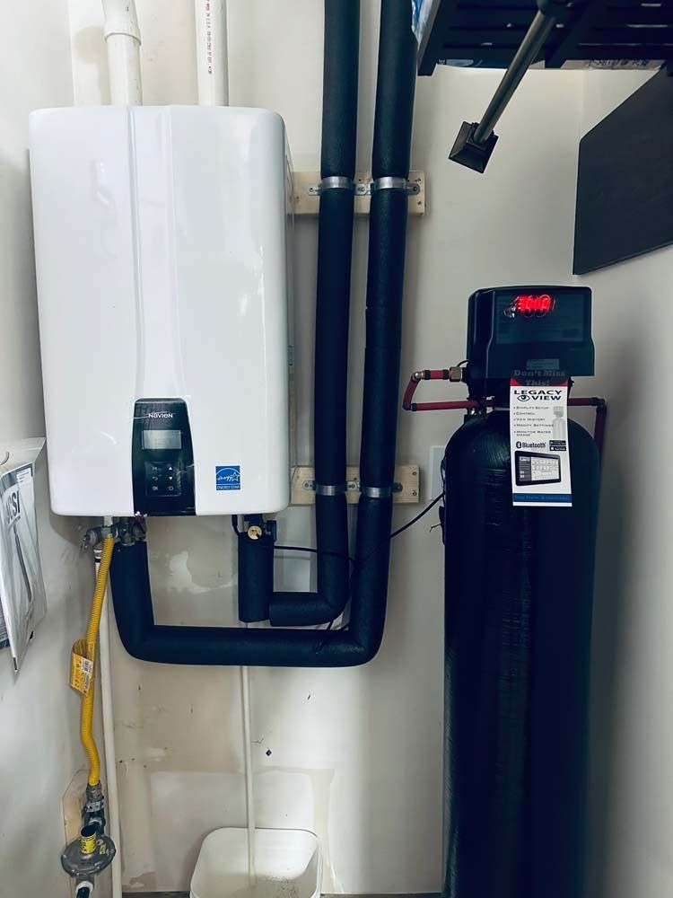 White water heater and black water softener against a white wall. Yellow gas line visible.