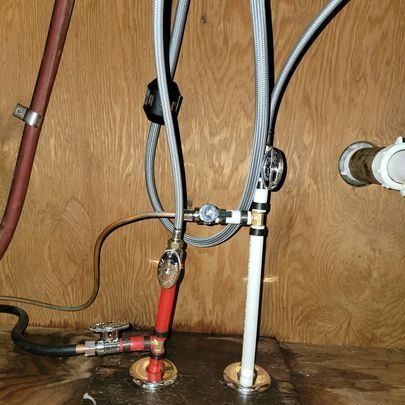 Under-sink plumbing with pipes and fixtures, including hot and cold water lines.
