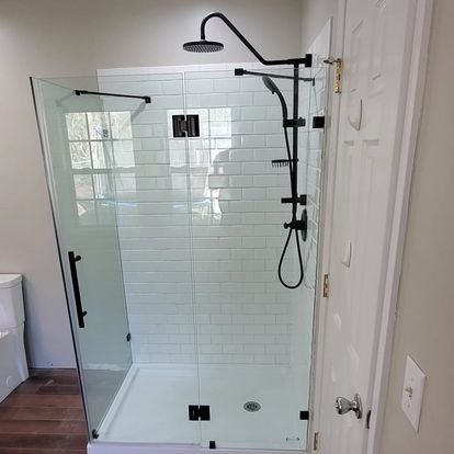 Modern shower with black fixtures and white subway tile walls. Clear glass door and side panel.