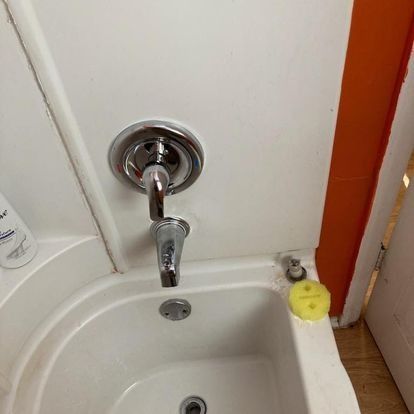 White bathtub with chrome faucet, drain, and a yellow sponge. Orange wall trim.