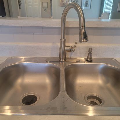 Stainless steel kitchen sink with faucet and soap dispenser.