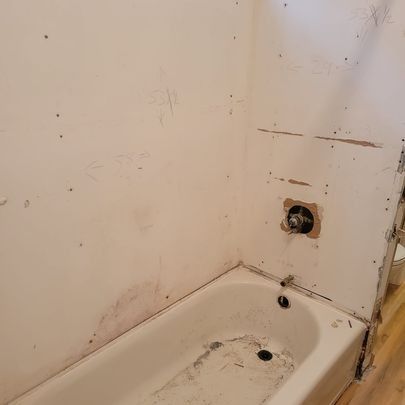 Bathroom remodel in progress; exposed walls around a white bathtub with a faucet and drain.