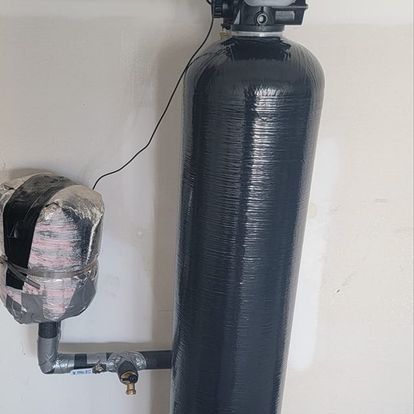 Water filtration system with black tank and insulated side tank, against a light wall.
