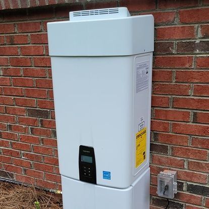 White solar battery system mounted on a red brick wall, with digital display and external outlet.