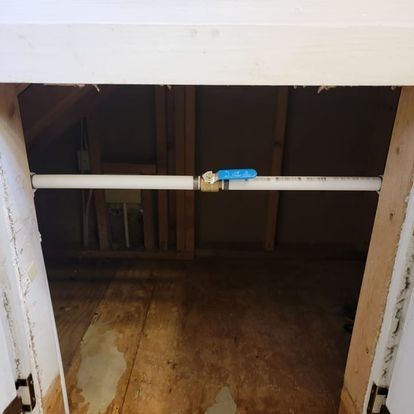 Water pipes with a blue valve in an attic space.