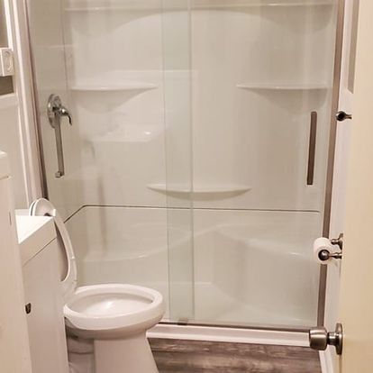 Bathroom with a white shower stall, toilet, and paper roll holder.